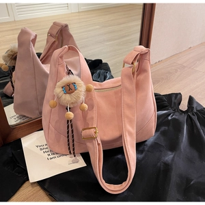 Detail of pink suede dumpling bag featuring a cute plush lion charm and mirror reflection