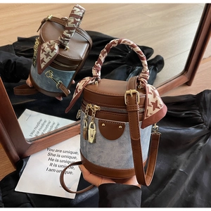 Detail of a retro bucket bag featuring brown leather, denim patchwork, and silk scarf