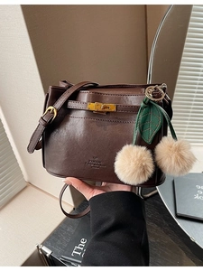 Deep brown minimalist crossbody bag with golden lock and plush cherry charm