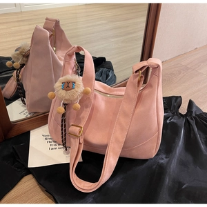 Close-up of pink suede hobo bag featuring a cute animal charm and gold zipper details