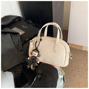 Detailansicht der cremefarbenen Retro-Handtasche mit Plüsch-Anhänger und Metallbeschlägen