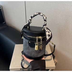 Detail of grey denim and black leather bucket bag with silk scarf on handle