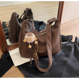Detailed view of brown soft leather dumpling bag with plush lion charm and golden buckle