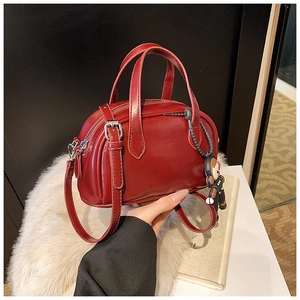 Details der roten glänzenden Boston-Handtasche mit Riemen und Cartoon-Anhänger