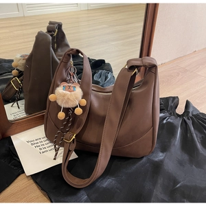 Detail of dark brown matte PU hobo bag with gold zipper and cute bear charm pendant