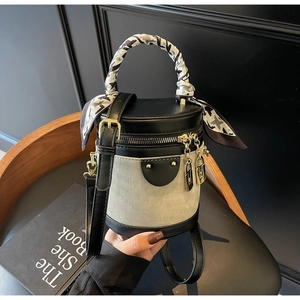 Detail of color-block cylinder bucket bag with scarf-wrapped handle and metal lock