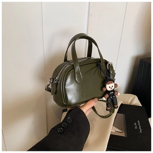Detail der dunkelgrünen glänzenden Leder-Mini-Boston-Tasche mit süßem Anhänger