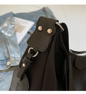 Detail of high-density nylon black shoulder bag with silver hardware and leather trim