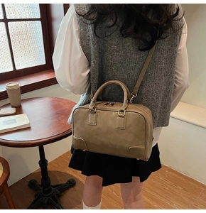 Detail view of olive green Boston bag featuring gold-tone hardware and adjustable strap