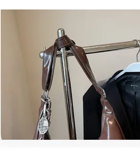 Detail of brown glossy leather tote bag featuring a knotted handle and tennis racket charm