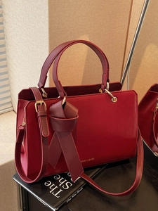 Elegante tiefrote Ledertasche mit verstellbarem Gurt und dekorativem Knotendetail