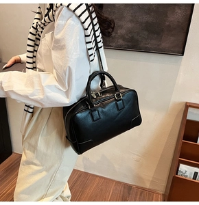 Close-up of minimalist black leather Boston bag with gold zippers and fine stitching