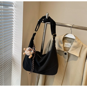 Detail of black dumpling shoulder bag with fluffy alpaca charm on a metal stand
