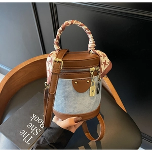Detail of retro cylinder bucket bag with contrast leather, denim, and scarf-wrapped handle