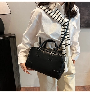 Close-up of a classic black Boston handbag with golden hardware and twin top handles