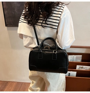 Detail of a black Boston bag featuring smooth leather texture and gold hardware zipper