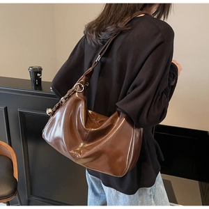 Detail of a large brown leather tote bag with silver chain and metal ring accents