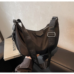 Detail of black nylon dumpling bag with adjustable logo strap and silver zipper closure