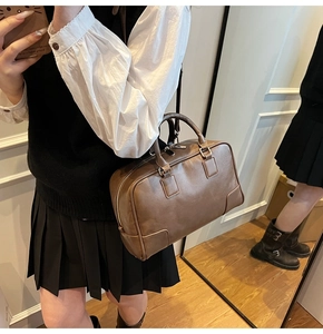 Detailed close-up of dark brown leather Boston bag with silver zipper and sturdy handles