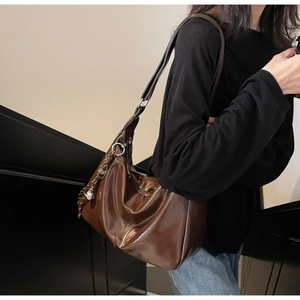Detail of glossy brown leather hobo bag with silver buckle and woven strap ornament
