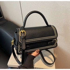 Close-up of black lychee grain leather with gold rivets and metallic hardware details