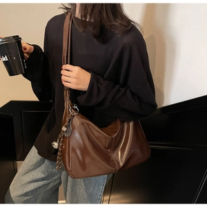 Detail of a large dark brown PU leather tote bag with a metallic tennis racket pendant charm
