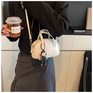 Detail der cremeweißen Mini-Boston-Tasche mit Anhänger getragen vom Modell