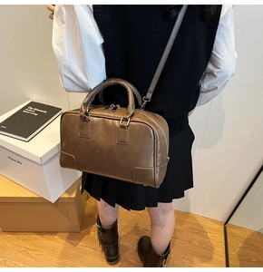 Detail of dark brown leather Boston bag with rounded corner patches and crossbody strap
