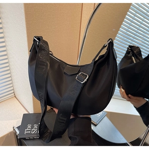 Detail of black nylon dumpling bag featuring adjustable wide strap and metallic zipper