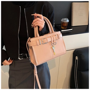 Detail of pink faux leather crossbody bag with decorative strap and key charm