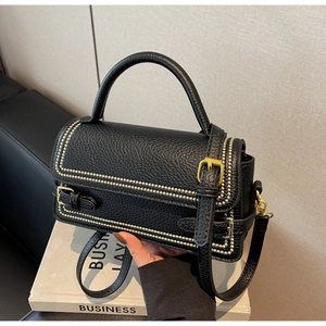 Detailed shot of black lychee grain leather bag with elegant gold stud trim and hardware