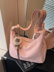 Pink suede dumpling crossbody bag with adjustable wide strap and plush bear charm