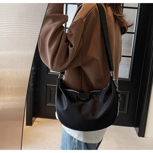 Detail of black nylon hobo bag with wide shoulder strap and leather logo patch