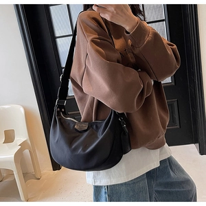 Detail of black nylon hobo bag with adjustable wide strap and subtle logo patch