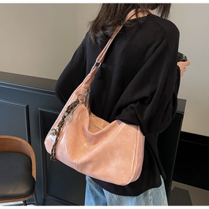 Pink glossy faux leather tote bag with decorative charms shown on a female model