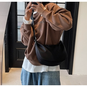 Mirror selfie showing a black nylon crescent crossbody bag styled with casual streetwear