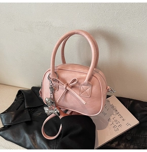 Dettaglio della mini borsa bowling rosa chiaro con fiocco e ciondolo a farfalla argento
