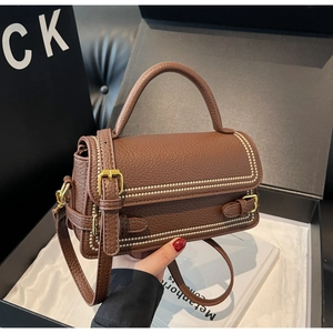 Detail view of brown pebbled leather handbag with pearled trim in luxury gift box