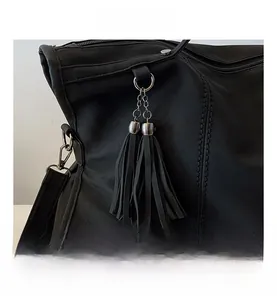 Detail of black tote bag featuring leather tassels with silver metal chain and round rivets