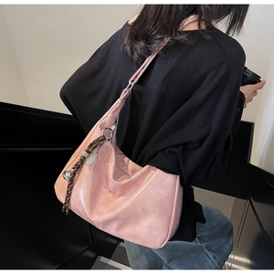 Detailed shot of pink glossy PU hobo bag featuring woven rope and metallic tennis pendant