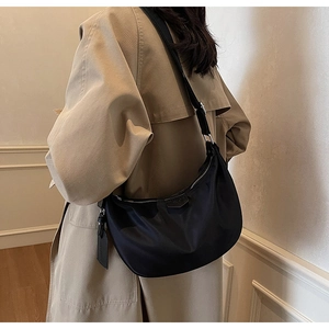Detail of black crescent hobo bag with nylon texture and adjustable silver metal buckle strap