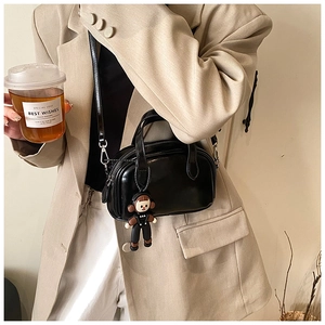 Modell-Styling der schwarzen Leder-Pillow-Bag mit Gurt und Puppenanhänger