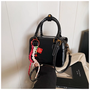 Detail of black leather Boston bag featuring white contrast stitching and gold hardware