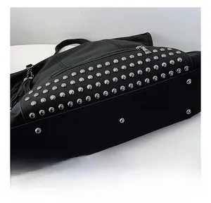 Close-up of black tote bag bottom featuring silver rivets and metal protective feet
