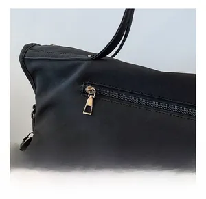 Detail shot of the smooth metal zipper and matte black texture on a vintage tote bag