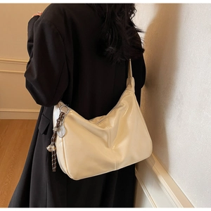 Detail of cream hobo bag with unique tennis racket metal charm and woven strap detail