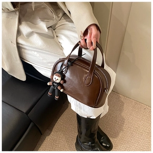 Detailansicht der kaffeebraunen Boston-Tasche aus Glattleder mit süßem Puppenanhänger