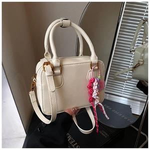 Detail of cream white leather bowling bag with gold hardware and woven tassel charm