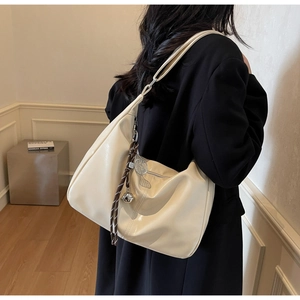 Detail of cream large Hobo shoulder bag featuring chic metallic charms and glossy leather