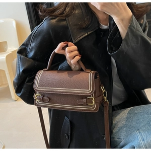 Detail of vintage brown textured leather handbag featuring white bead trim and gold hardware